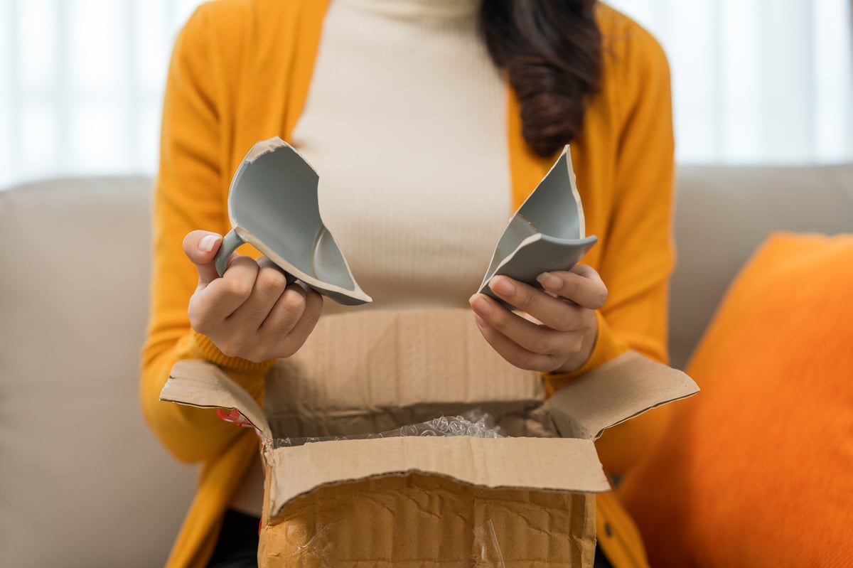 Person unpacking household items including plates and ceramic cups ordered online
